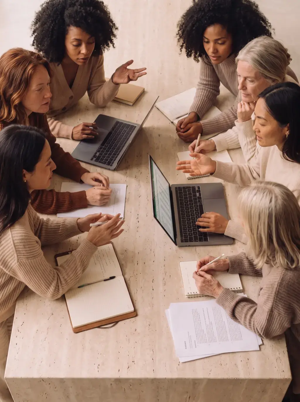 Vue de dessus d'une réunion de sept femmes autour d'une grande table en travertin