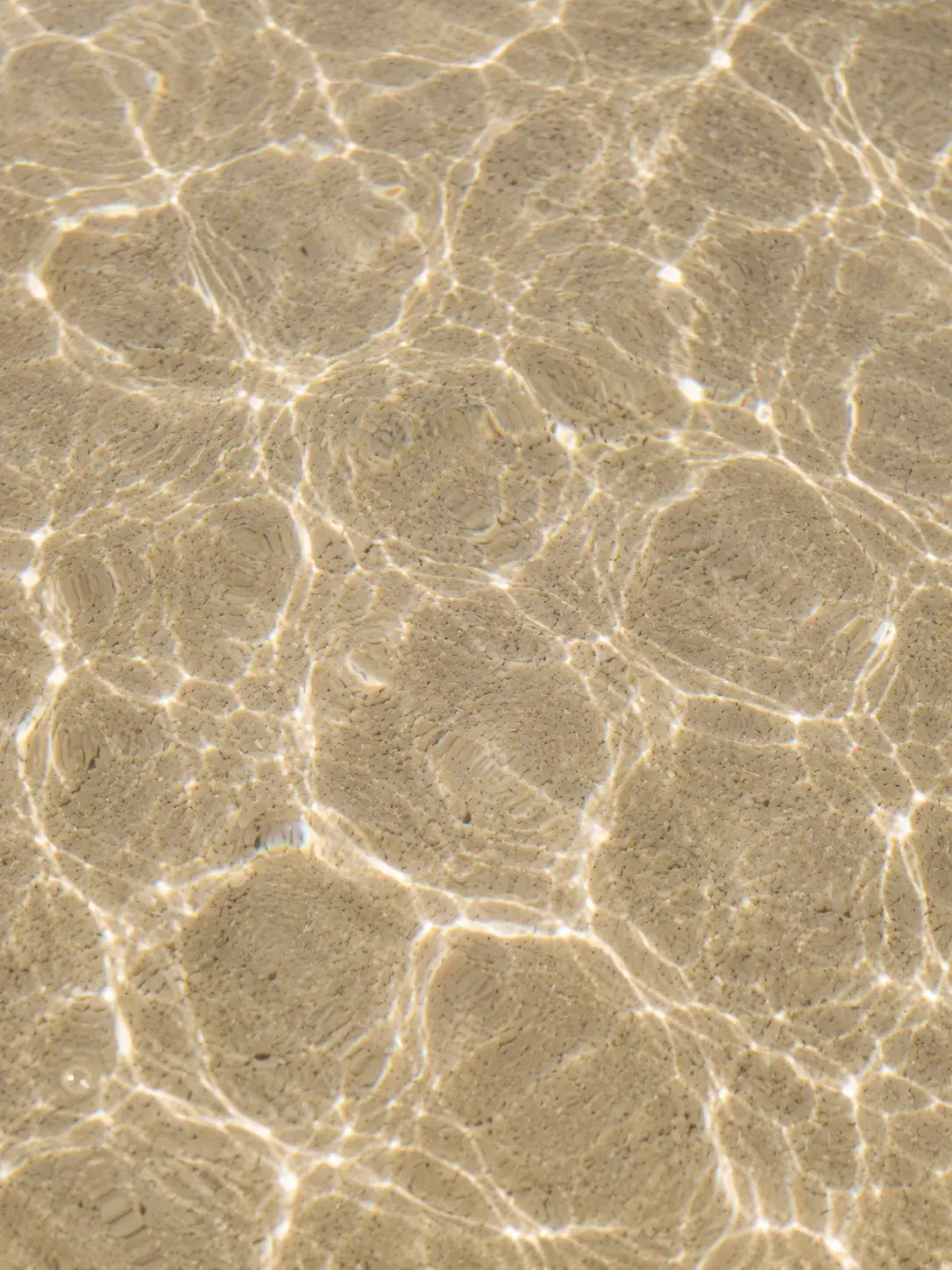 Vue de dessus fond de mer peu profonde – reflets de lumière sur sable, miroitement aquatique