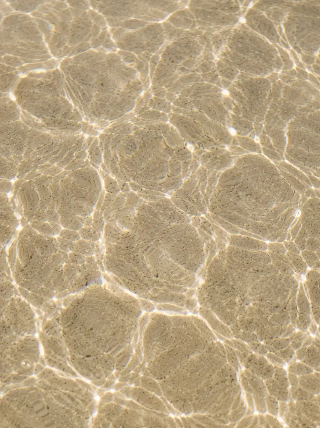 Vue de dessus fond de mer peu profonde – reflets de lumière sur sable, miroitement aquatique