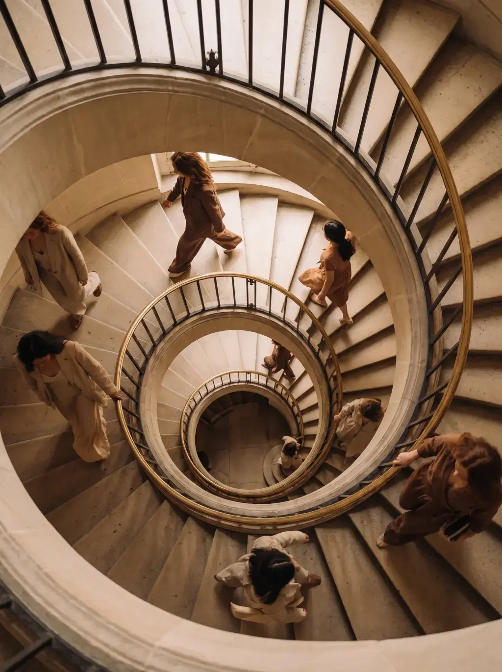 Vue plongeante d'un grand escalier en colimaçon avec groupe de femmes en tenues neutres