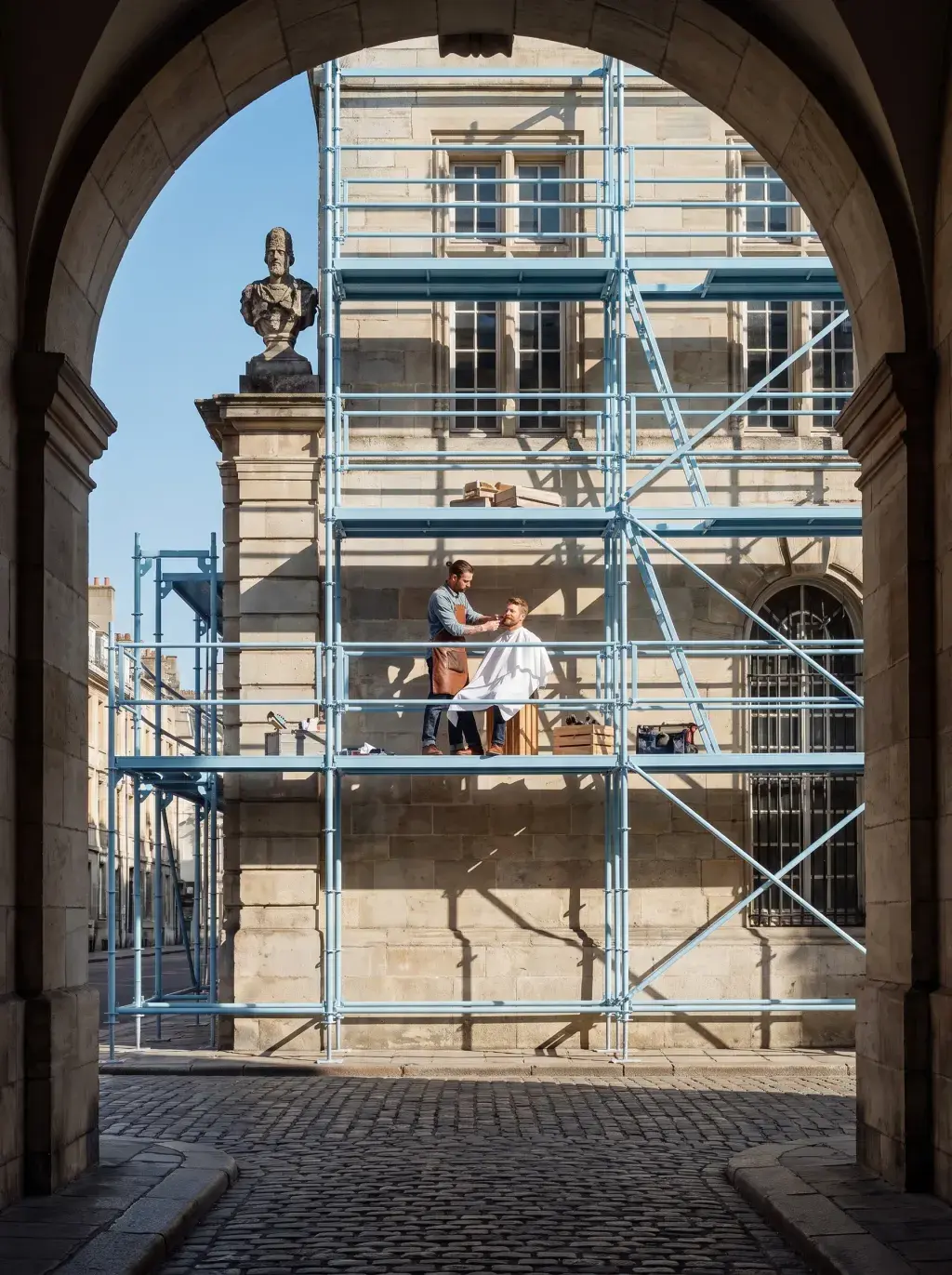 Coiffeur coupant les cheveux d'un client installé sur un échafaudage, vue à travers une arche en pierre historique