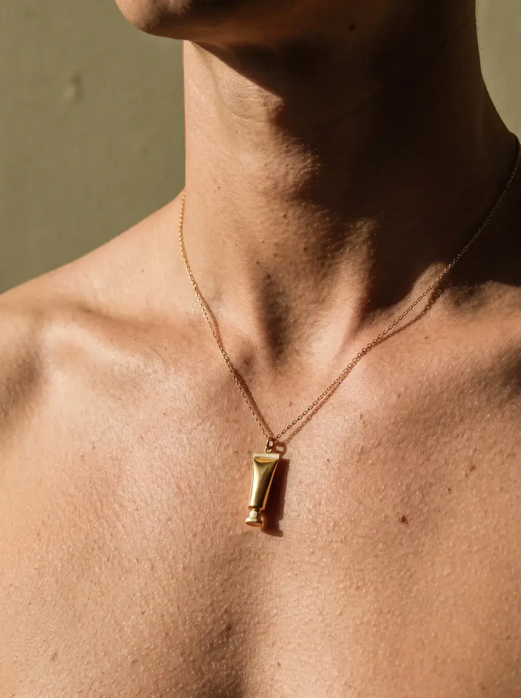 Buste de femme portant un pendentif en forme de mini tube cosmétique jaune