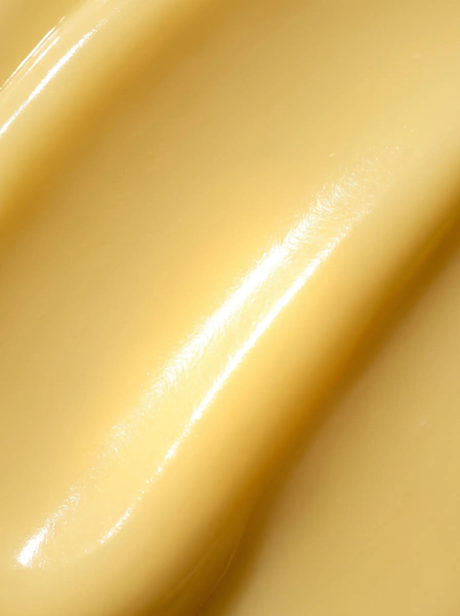 Macro d’une surface de crème jaune parfaitement lisse et brillante