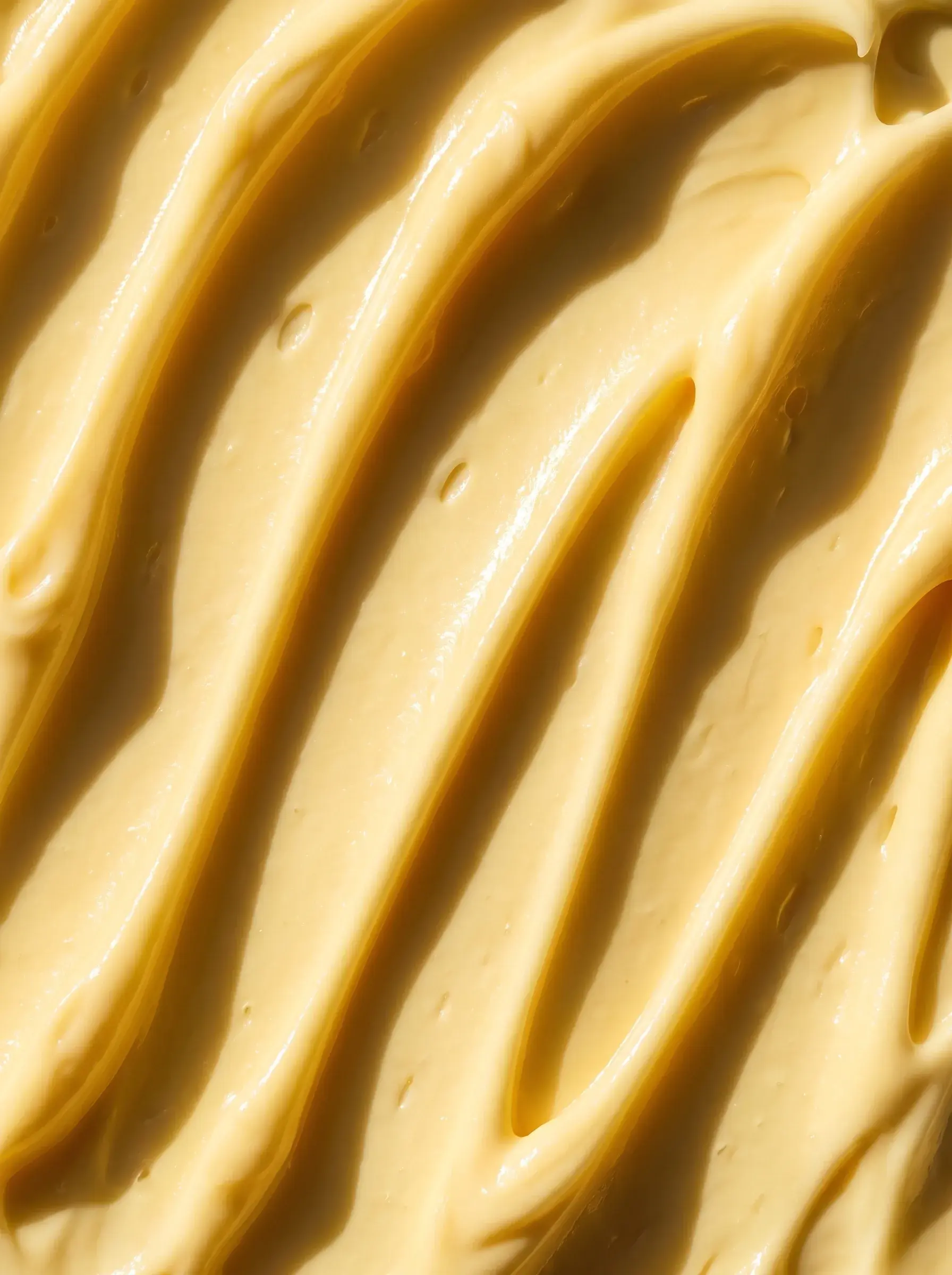 Macro de sillons ondulés creusés dans une crème cosmétique jaune