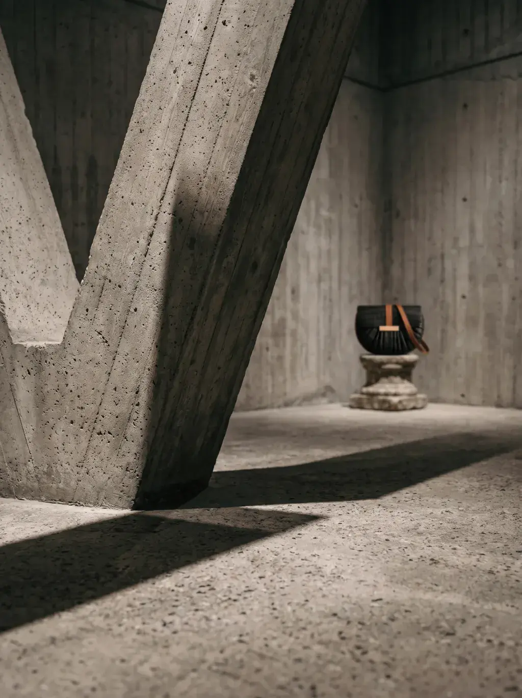 Petit sac noir exposé au loin dans une structure brutaliste monumentale