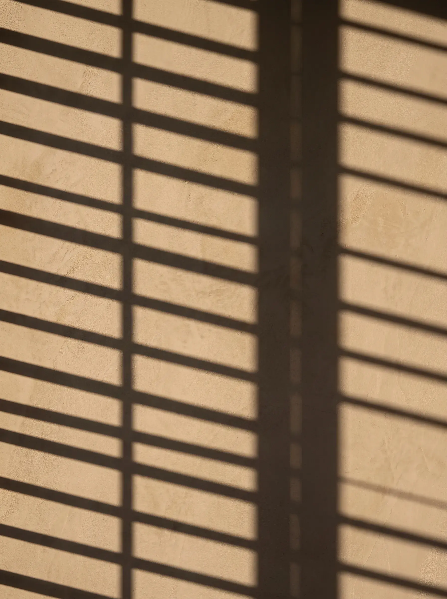 Ombres régulières de stores projetées sur un mur beige
