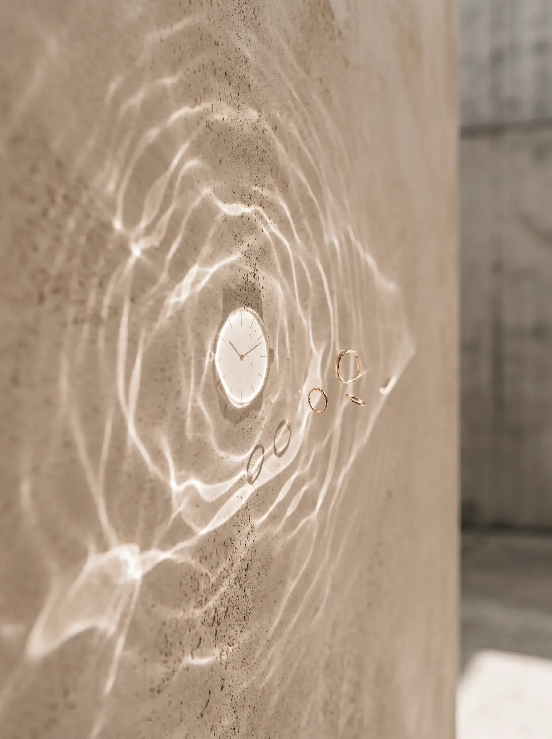 Ondes lumineuses circulaires autour d’un petit médaillon sur un mur beige