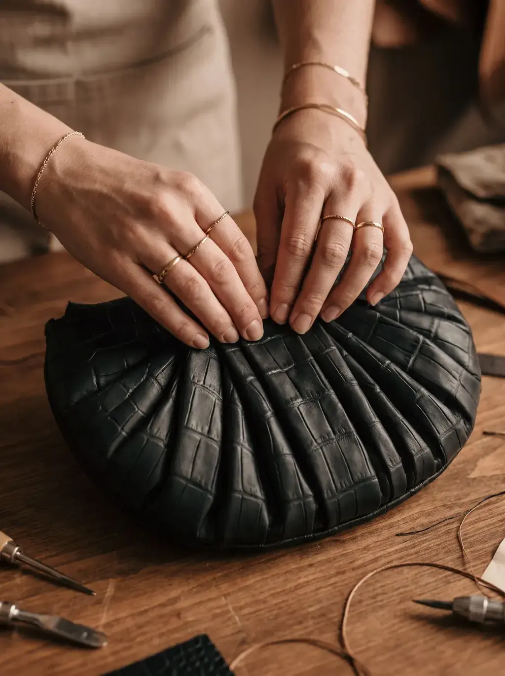 Mains d’artisane formant les plis circulaires d’un sac noir sur un établi