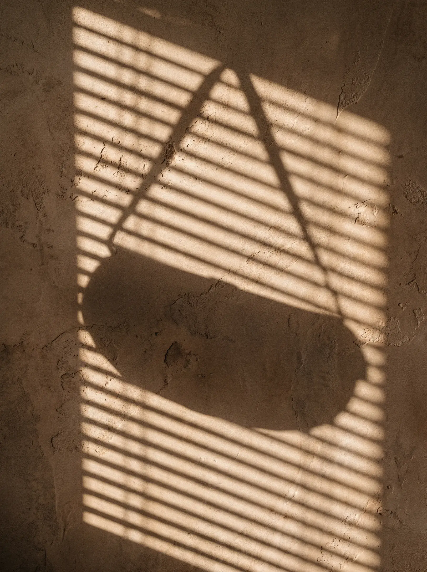 Ombre abstraite d’un sac à bandoulière projetée sur un mur beige