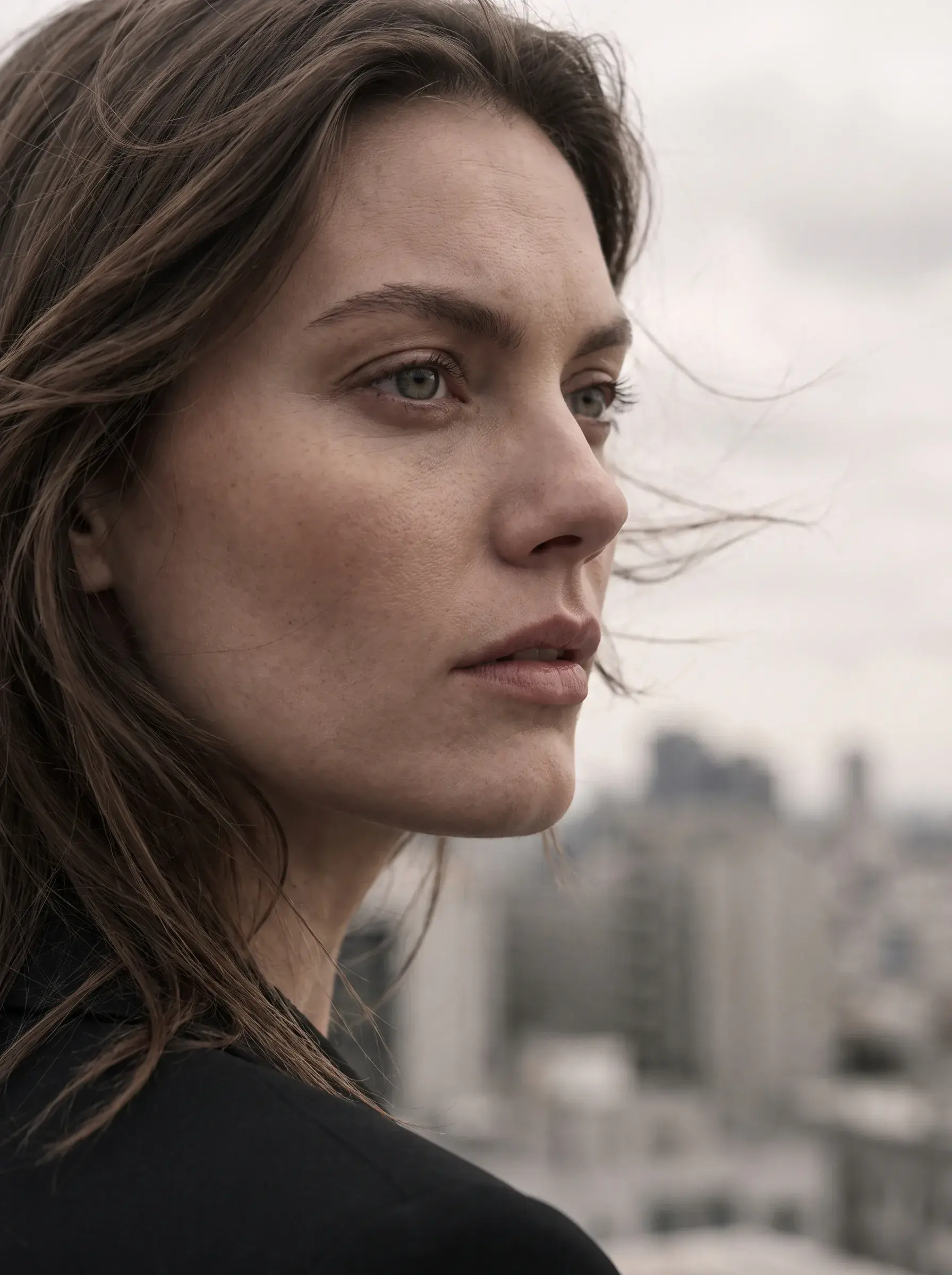 Portrait d’une femme aux cheveux dans le vent devant une ville floue