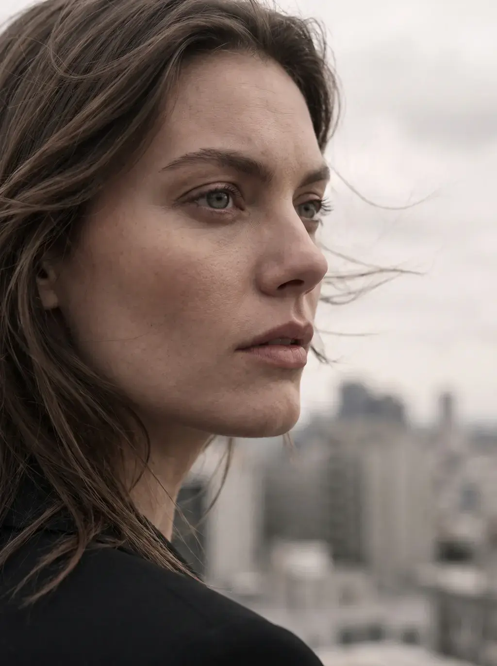 Portrait d’une femme aux cheveux dans le vent devant une ville floue