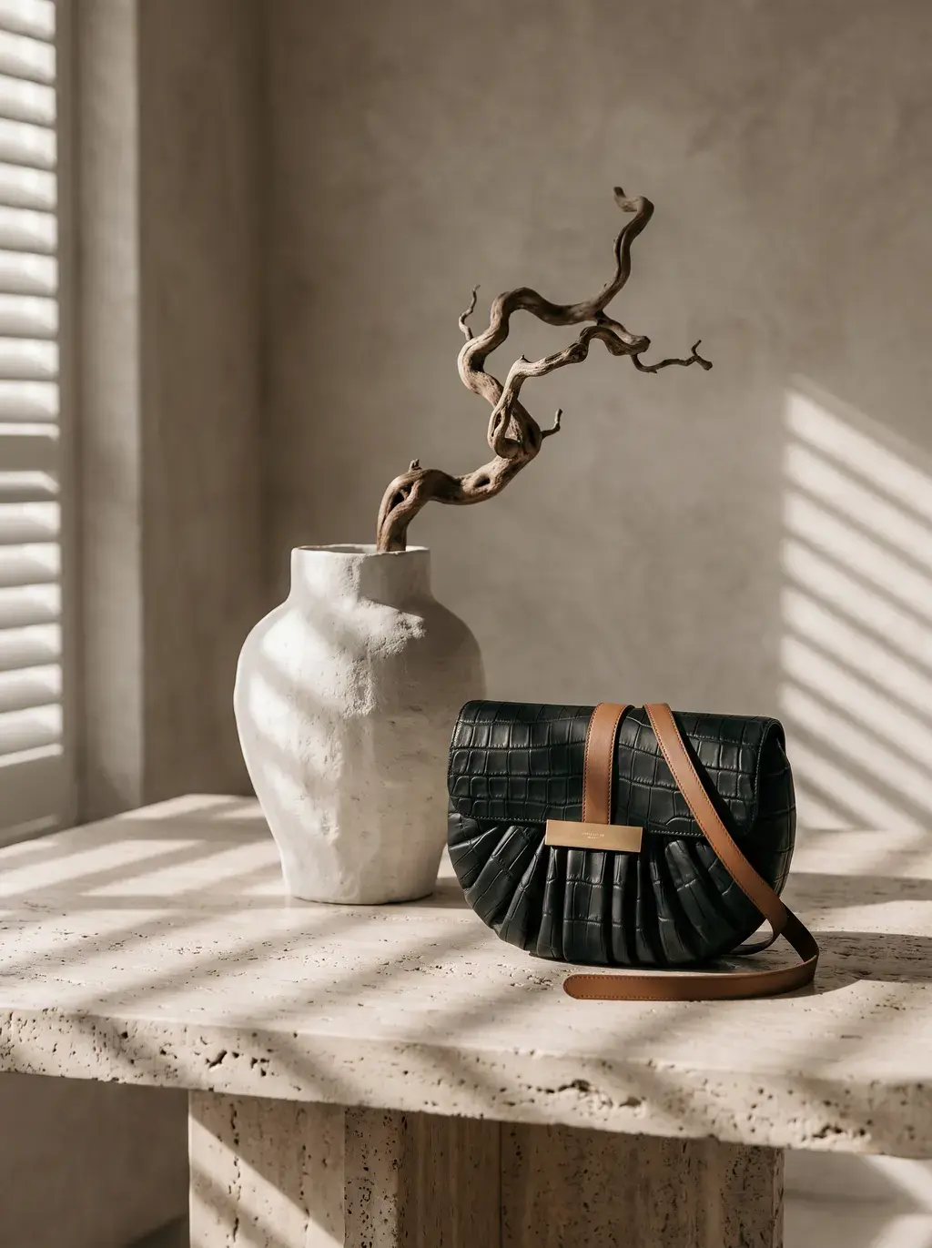 Sac croco et vase céramique blanc avec bois flotté sur table travertin