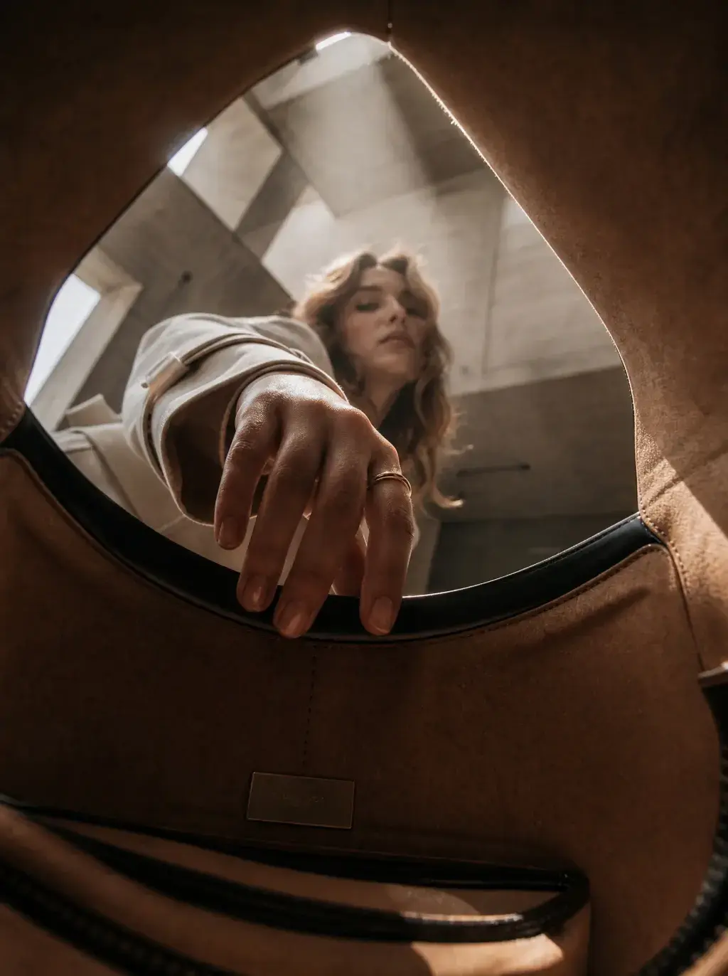 Vue depuis l’intérieur d’un sac en cuir brun pendant qu’une femme y glisse la main