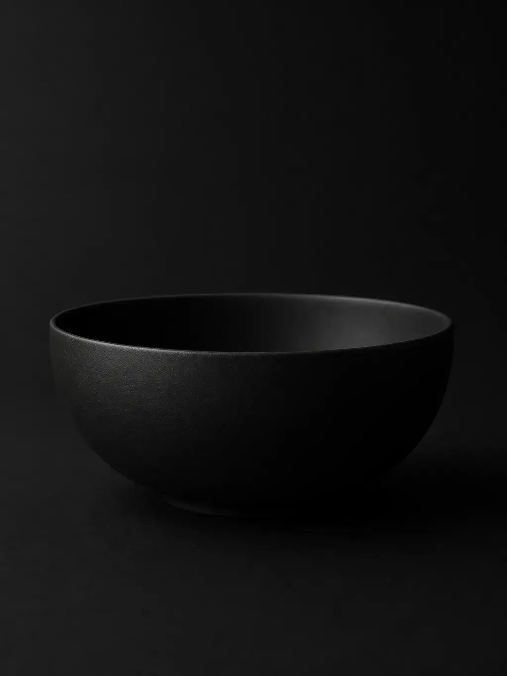 Grand bol en céramique noire sur fond noir épuré