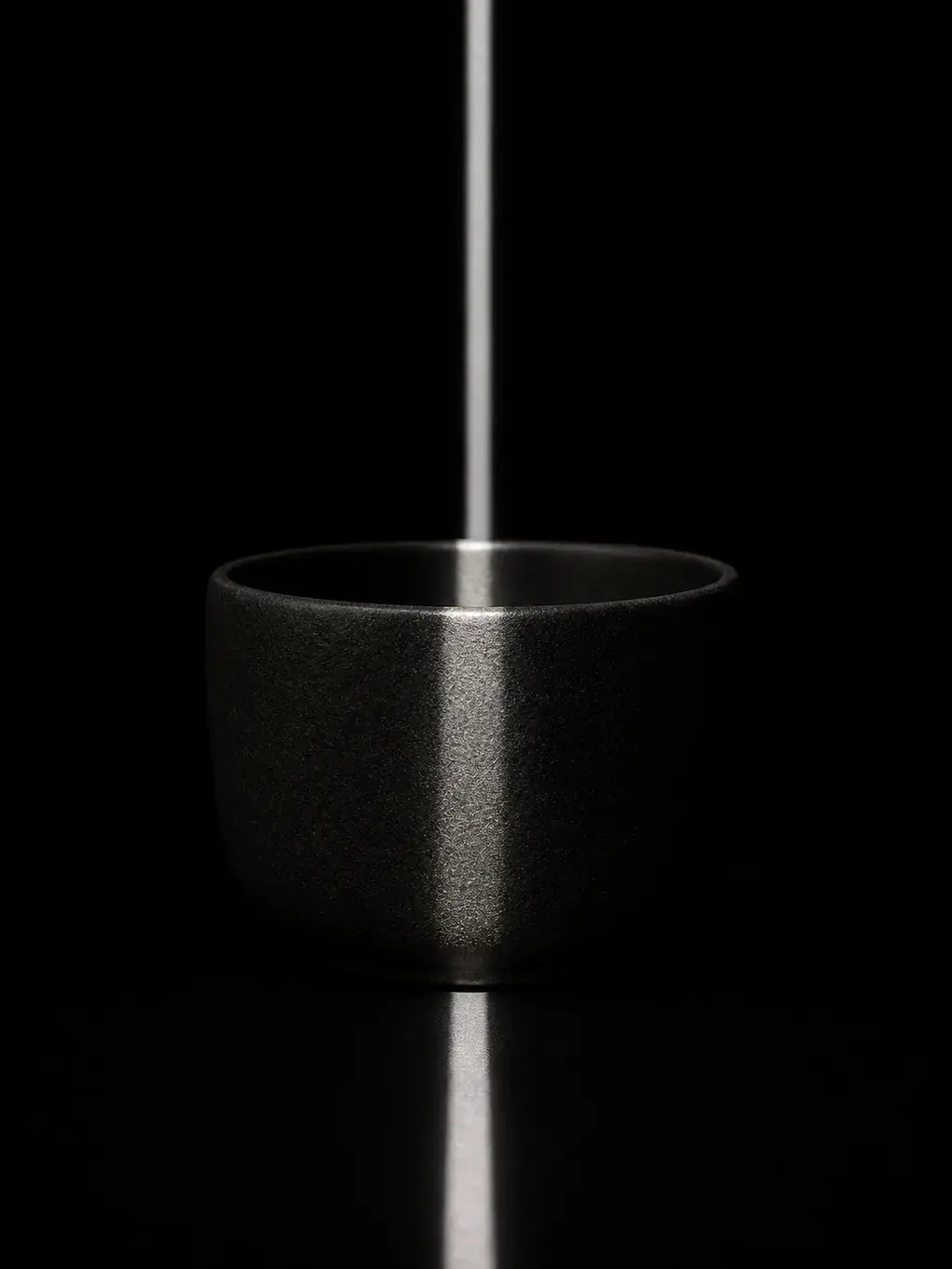 Tasse céramique noire avec rayon de lumière vertical sur fond noir