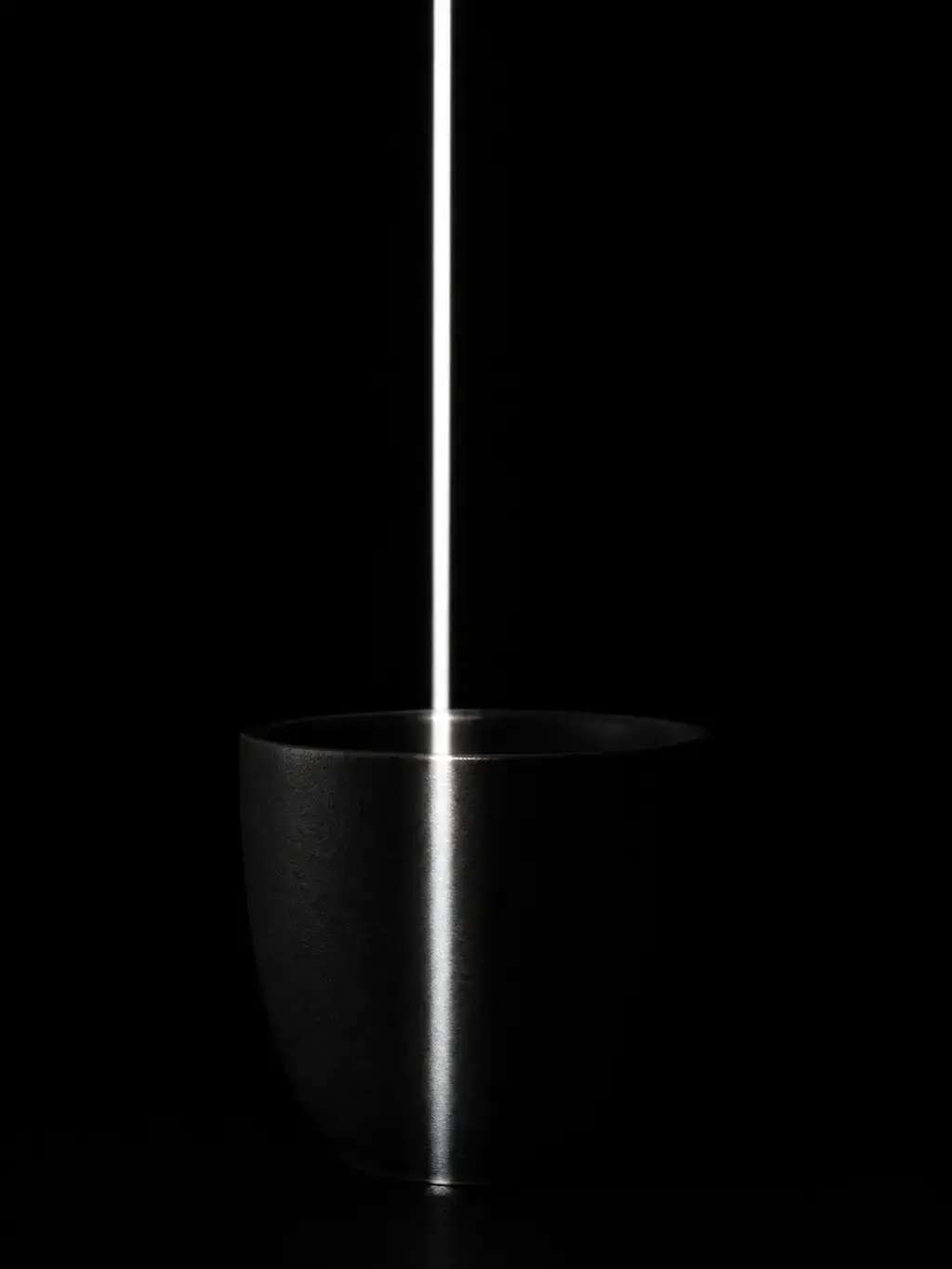Bol en céramique noire éclairé par un trait de lumière vertical