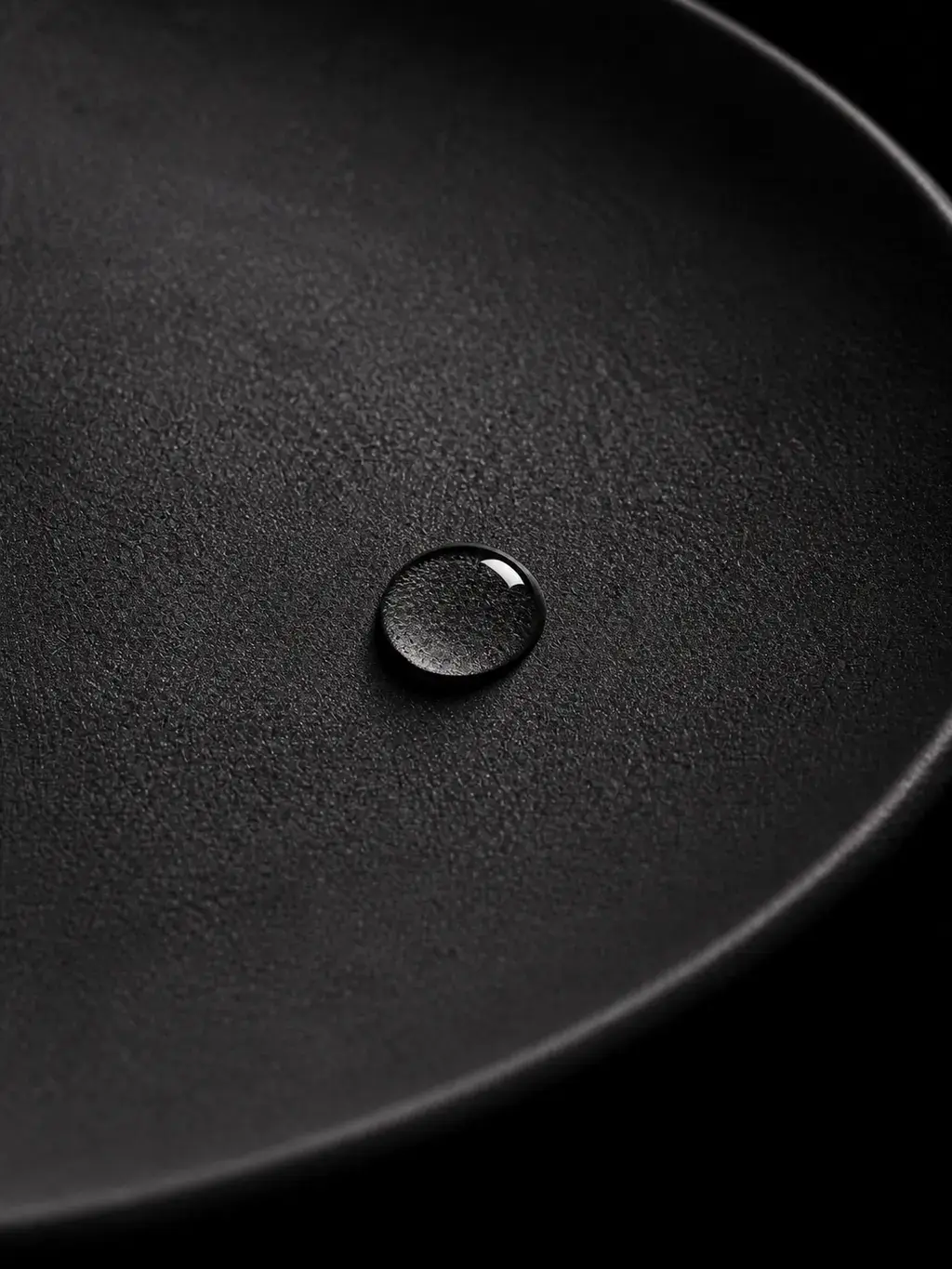 Goutte d'eau sur assiette en céramique noire texturée, macro